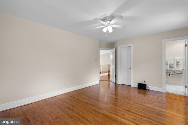 unfurnished bedroom featuring baseboards, ensuite bath, and wood finished floors
