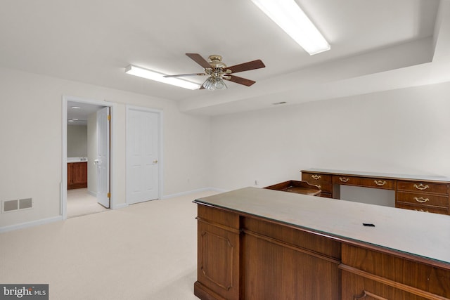 interior space with visible vents, baseboards, light colored carpet, light countertops, and a ceiling fan