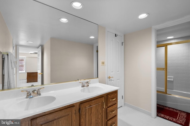bathroom featuring a sink, bath / shower combo with glass door, recessed lighting, and double vanity