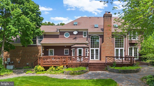 back of house with roof with shingles, a chimney, and a deck