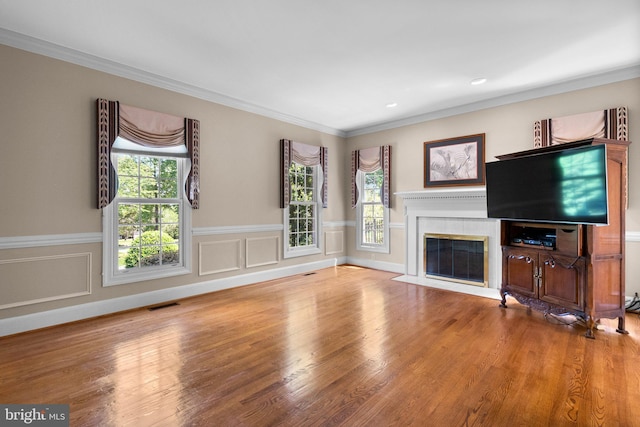 unfurnished living room with a healthy amount of sunlight, wood finished floors, a fireplace with flush hearth, and visible vents