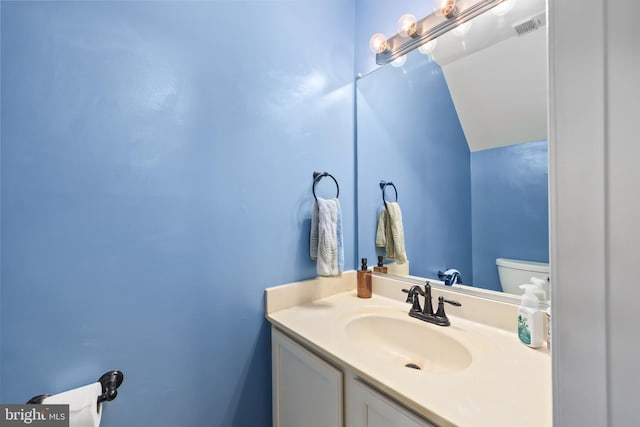 half bath featuring toilet, visible vents, vaulted ceiling, and vanity