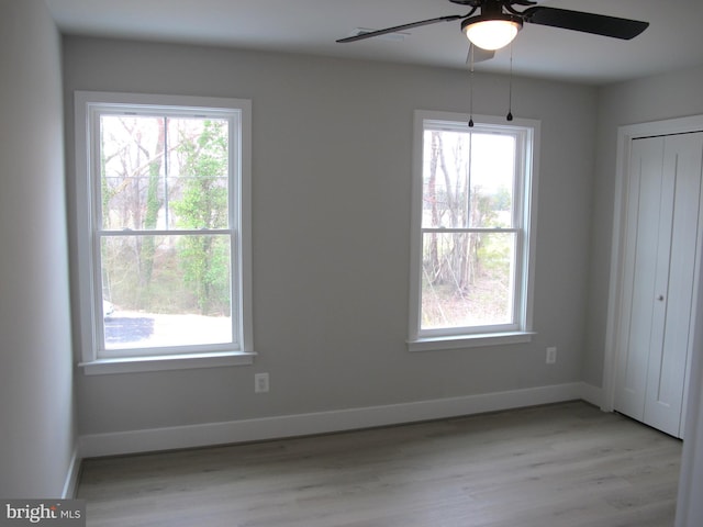 unfurnished bedroom with baseboards, multiple windows, and light wood-type flooring