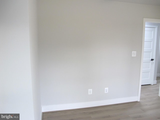 spare room with baseboards and wood finished floors