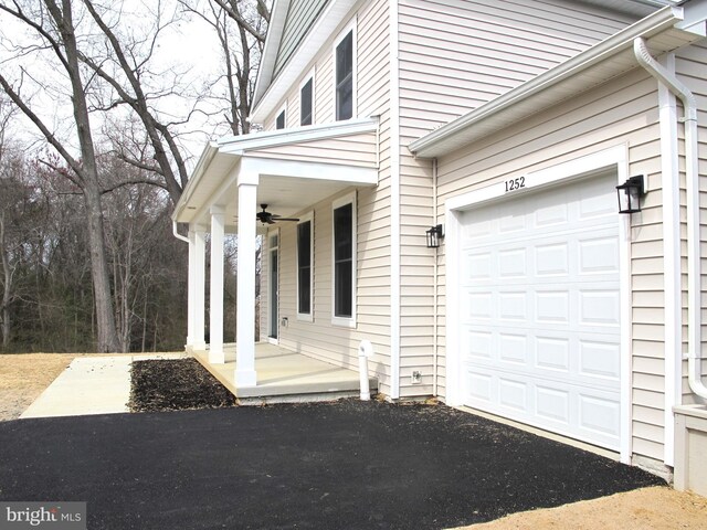 property entrance with an attached garage, aphalt driveway, a porch, and a ceiling fan