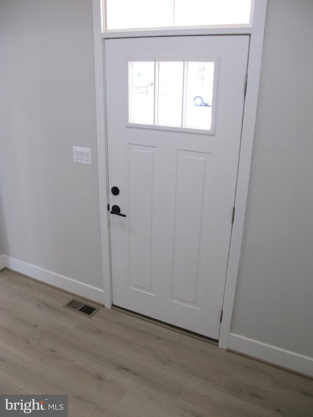 entryway with baseboards, visible vents, and wood finished floors