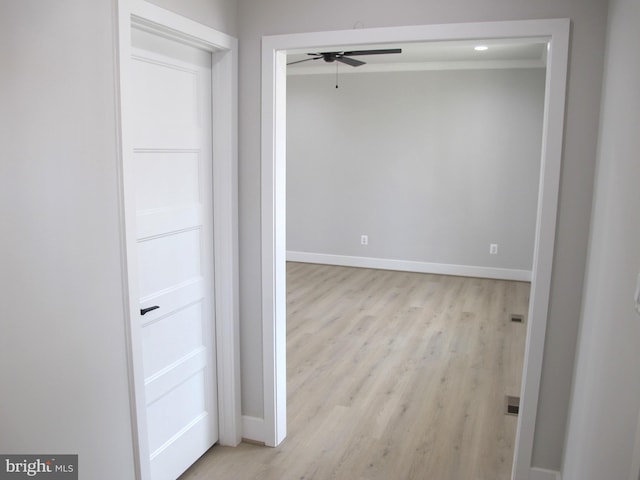 corridor with baseboards and light wood finished floors