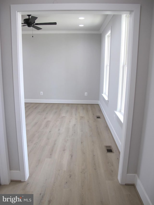 spare room featuring ornamental molding, baseboards, light wood finished floors, and visible vents