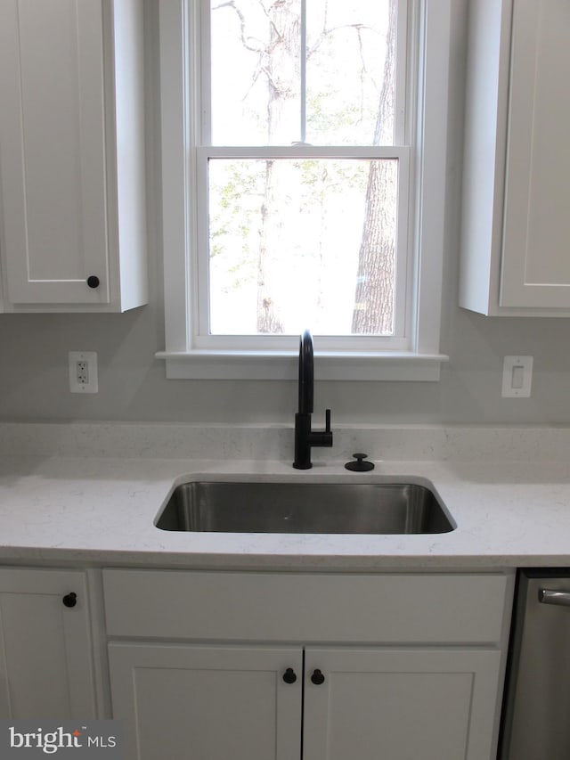 kitchen featuring white cabinetry, a sink, light stone countertops, and dishwasher