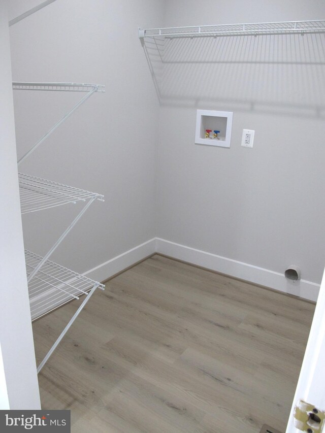 clothes washing area featuring hookup for a washing machine, baseboards, laundry area, and wood finished floors