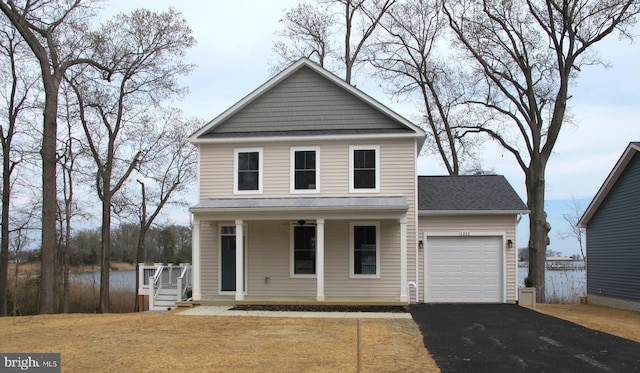 traditional-style home featuring driveway, an attached garage, a shingled roof, and covered porch