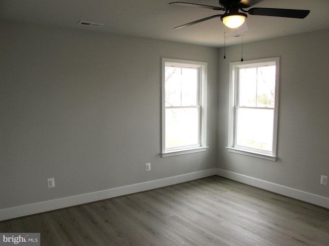 empty room featuring baseboards, ceiling fan, visible vents, and wood finished floors