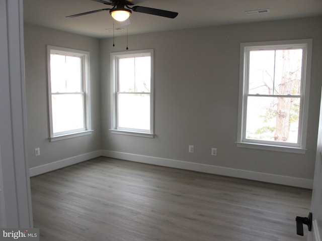 unfurnished room with visible vents, a wealth of natural light, and ceiling fan
