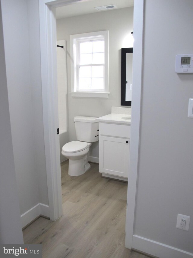 full bath with visible vents, a shower, toilet, wood finished floors, and vanity