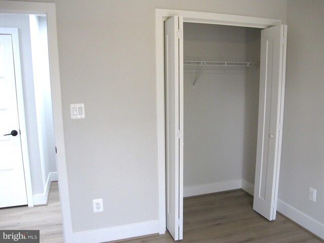 unfurnished bedroom with a closet, baseboards, and wood finished floors
