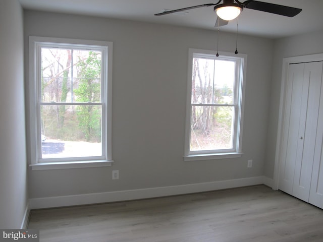 unfurnished bedroom with light wood-style floors, baseboards, and multiple windows