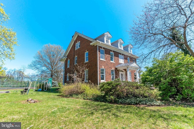 view of side of property featuring brick siding, a yard, and a playground