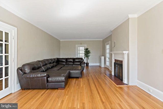 living area with light wood-type flooring, a brick fireplace, and crown molding
