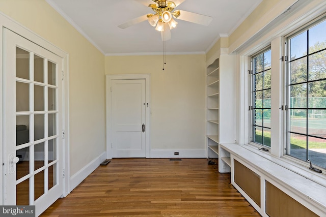 interior space with baseboards, wood finished floors, ornamental molding, and ceiling fan