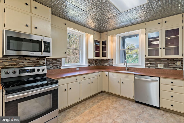kitchen featuring a sink, an ornate ceiling, plenty of natural light, appliances with stainless steel finishes, and cream cabinets