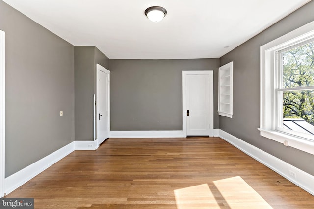 spare room featuring baseboards and light wood finished floors