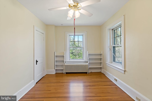 spare room with radiator heating unit, wood finished floors, and a healthy amount of sunlight