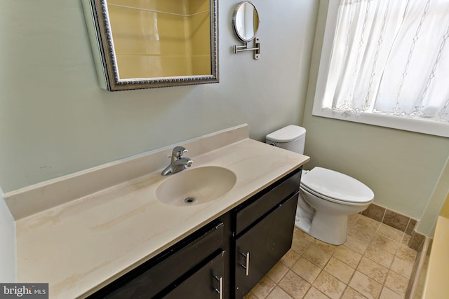 bathroom featuring stone tile floors, vanity, and toilet