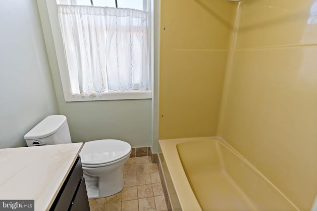 full bath with stone tile flooring, toilet, vanity, and a healthy amount of sunlight