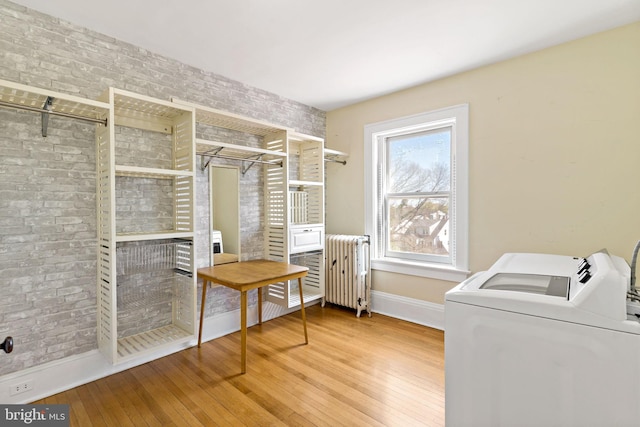 laundry area featuring radiator heating unit, washer and clothes dryer, laundry area, wood-type flooring, and baseboards