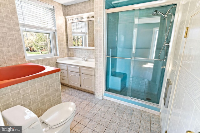 full bathroom with a shower stall, vanity, tile walls, toilet, and tile patterned flooring