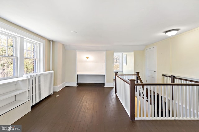 hall featuring baseboards, radiator heating unit, hardwood / wood-style flooring, and an upstairs landing