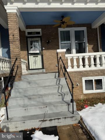 snow covered property entrance with brick siding
