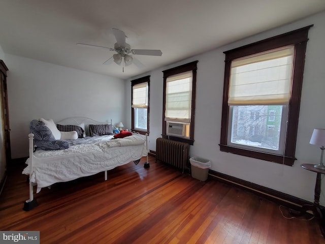 bedroom with cooling unit, radiator heating unit, wood-type flooring, baseboards, and ceiling fan