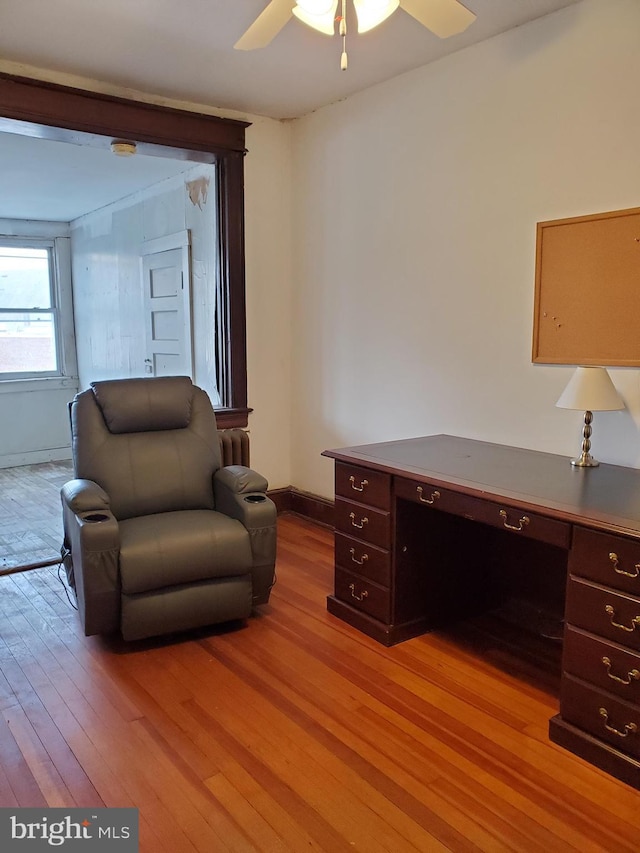 office space with baseboards, built in desk, light wood-style floors, and a ceiling fan