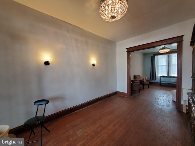 interior space featuring an inviting chandelier, baseboards, and dark wood finished floors