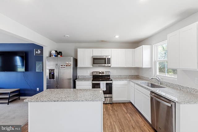 kitchen featuring a sink, a center island, appliances with stainless steel finishes, and white cabinetry