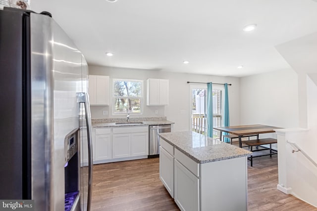 kitchen with light wood-style floors, white cabinetry, a center island, a sink, and stainless steel appliances