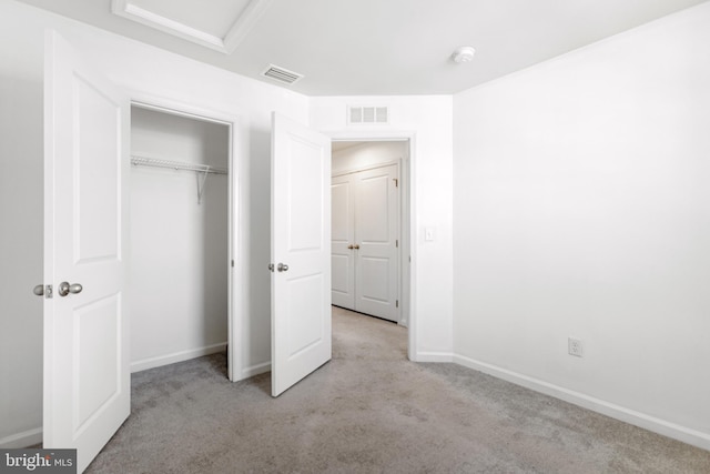 unfurnished bedroom featuring visible vents, baseboards, a closet, attic access, and carpet flooring