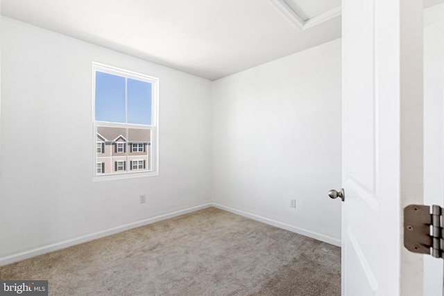 spare room featuring baseboards, carpet flooring, and attic access