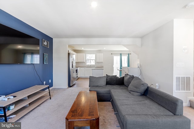living area featuring light carpet, baseboards, visible vents, and recessed lighting