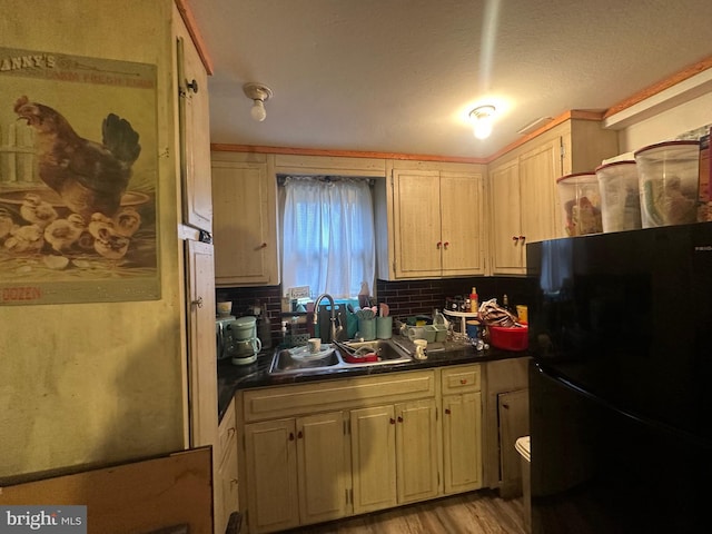 kitchen featuring dark countertops, a sink, light wood-type flooring, backsplash, and freestanding refrigerator