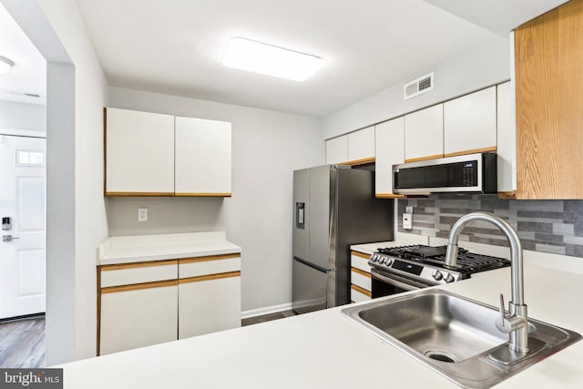 kitchen with a sink, visible vents, backsplash, light countertops, and appliances with stainless steel finishes
