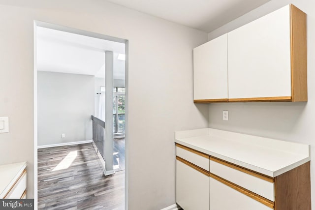 kitchen featuring light countertops, white cabinets, dark wood-style floors, and baseboards