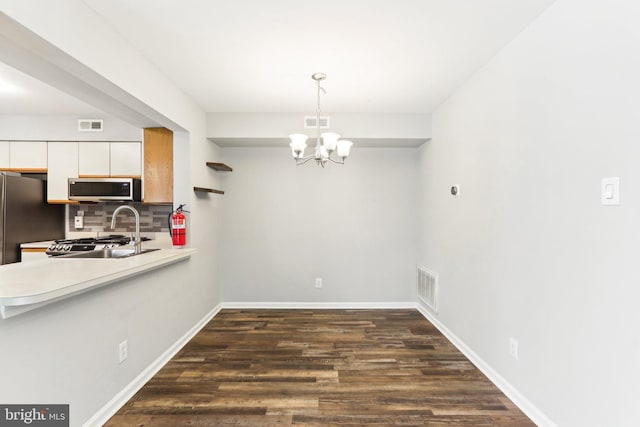 unfurnished dining area featuring an inviting chandelier, visible vents, and dark wood-type flooring