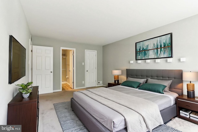 carpeted bedroom with ensuite bath and baseboards