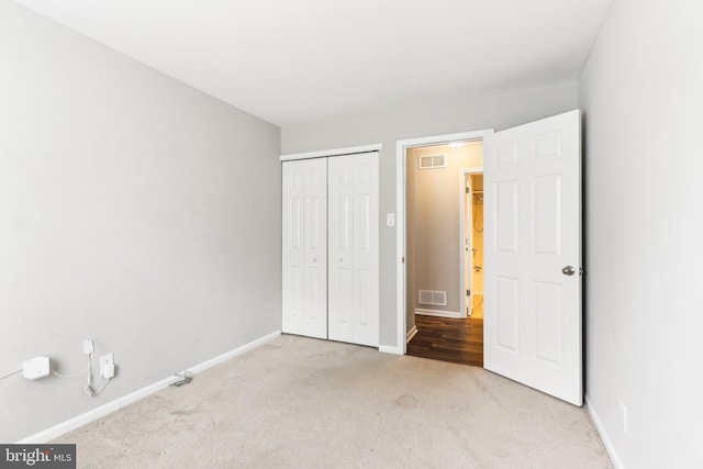 unfurnished bedroom featuring carpet, visible vents, a closet, and baseboards