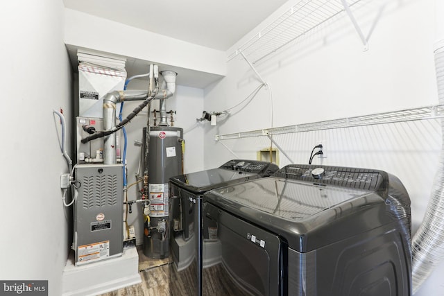 washroom with water heater, wood finished floors, washer and clothes dryer, and laundry area