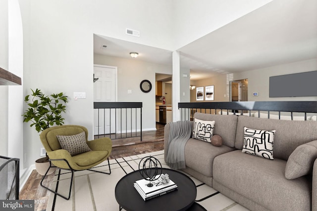 living area featuring visible vents, wood finished floors, and baseboards