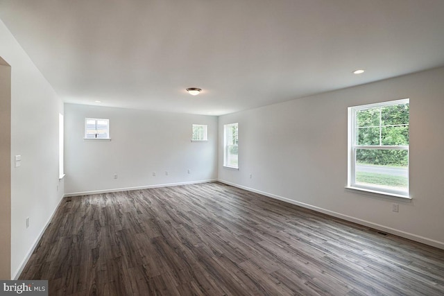 spare room with dark wood-style flooring, visible vents, baseboards, and recessed lighting