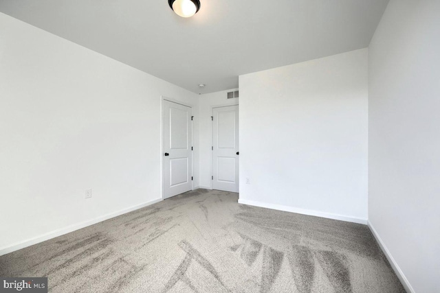 carpeted empty room with visible vents and baseboards